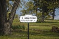 Directional sign on pole saying Parking this way and Ranch Hands only with arrows against blurred woodland background