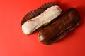 French desserts eclairs with white chocolate and dark chocolate on top filled with custard served on red background Royalty Free Stock Photo