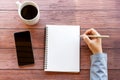 Directly above hand holding pen with blank note pad, smart phone and cup of coffee Royalty Free Stock Photo