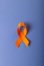 Directly above shot of orange leukemia awareness ribbon isolated over blue background, copy space