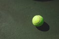 Directly above view of green tennis ball with shadow on gray court during sunny day Royalty Free Stock Photo