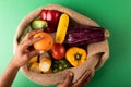 Directly above view of mixed race man hand holding fresh orange fruit over vegetables in burlap sack