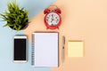 Office desk with computer keyboard, cup of coffee,smart phone, alarm clock, sticky notes, pot of plant Royalty Free Stock Photo