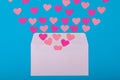 Directly above view of pink hearts coming out from white envelope blue background, copy space Royalty Free Stock Photo