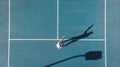 Directly above view of young caucasian female player playing on blue tennis court during sunny day Royalty Free Stock Photo