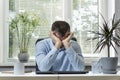 Director in his office rubs eyes wearily. Young man sits at the workplace and rubs his eyes. Work in the office and eye problem Royalty Free Stock Photo