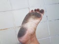 Dirt on bottom of foot and toes with white tile floor Royalty Free Stock Photo