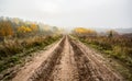 The dirt clay road rushes down and into the distance, dissolving in the fog.