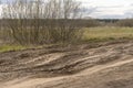 Dirt damaged rural spring road in a field. concept of problem with the roads