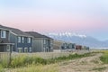 Dirt road along white fences of houses against snow capped mountain at sunset Royalty Free Stock Photo