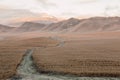 dirt road in field going into mountains. Dawn in autumn field. Hills in morning haze. Grass covered with autumn Royalty Free Stock Photo