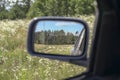 Dirt road and forest reflected in a car mirror Royalty Free Stock Photo