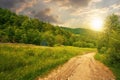 dirt road through forested countryside at sunset