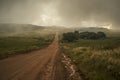 dirt road that goes away towards the cloudy mountains Royalty Free Stock Photo
