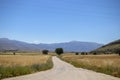 dirt road leading to the mountains in the country, there are fields on the side. and trafic signs Royalty Free Stock Photo