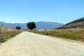 dirt road leading to the mountains in the country, there are fields on the side. and trafic signs Royalty Free Stock Photo