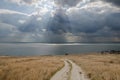 Dirt road leading to the sea and the dramatic clouds over the se Royalty Free Stock Photo