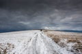 Dirt road leading to the top of the hill at wintertime, dramatic storm clouds Royalty Free Stock Photo