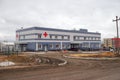 Dirt road leads to a city hospital building under construction at a project site on a cloudy autumn day