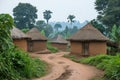 A dirt road lined with huts in a rural setting, A traditional African mud hut village, AI Generated Royalty Free Stock Photo