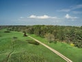 Dirt road in the meadow near the forest, blue sky on the background. aerial view Royalty Free Stock Photo