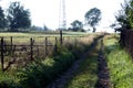 A dirt road in the mountains and an old fence overgrown with tall grass. Royalty Free Stock Photo