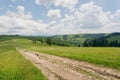 Dirt road on mountains under blue sky. Rural landscape with clouds Royalty Free Stock Photo