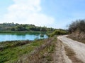 Dirt road near a small pond in Ugroidy village Sumy region, Ukraine. Fishing pier on the lake, swamp and rural estates on the Royalty Free Stock Photo