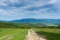 Dirt road near wood fence leading trough the countryside in the Carpathian mountains Royalty Free Stock Photo