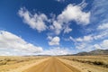 Dirt road in the Nevada desert under blue sky with clouds. Royalty Free Stock Photo