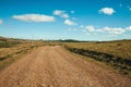 Dirt road passing through rural lowlands and ranch