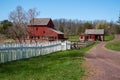 Dirt road with picket fence and a colonial American red barn and log cabin Royalty Free Stock Photo