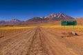 Dirt road with a road sign and mountains in the background, in the Atacama Desert, Chile Royalty Free Stock Photo