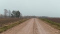 a dirt road running along side some grass and trees behind it Royalty Free Stock Photo