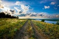 Dirt road in the steppe between feather fields grass and parallel with river