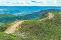 Dirt road on top of the hill surrounded by green nature. Royalty Free Stock Photo