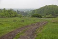 Dirt rural road among the green hills at countryside Royalty Free Stock Photo