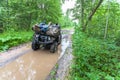 Dirty ATV stands with bags and stuff in the deep muddy puddle on the forest road