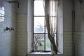 A dirty bathroom in an abandoned house of Chernobyl. Broken window with old curtain, feeling of depression in a crackhouse Royalty Free Stock Photo