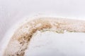 Dirty bathtub surface with a metal drain hole.