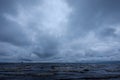 Dirty beach by the sea with storm clouds above in calm evening Royalty Free Stock Photo