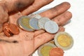 A dirty palm carrying coins on the white floor background.