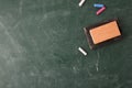 Dirty blackboard with white and colored chalk and eraser top