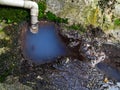 Dirty blue color water flow from a block drain pipe onto a ground, Ecology and environment protection concept Royalty Free Stock Photo