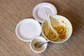 Dirty bowl of soup leftovers with spoon and plates on wooden table background. Top view with copy space for text