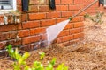 Dirty brick wall being cleaned with a pressure washer