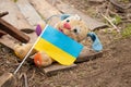 A dirty broken children`s toy and the flag of Ukraine lies in the yard during the war in Ukraine, the death of children at the