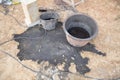 dirty bucket of oil standing in a black puddle near a construction site Royalty Free Stock Photo