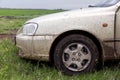 The dirty car costs on a green grass.