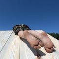 Dirty children feet hang down when child climbs over fence or on roof. Royalty Free Stock Photo